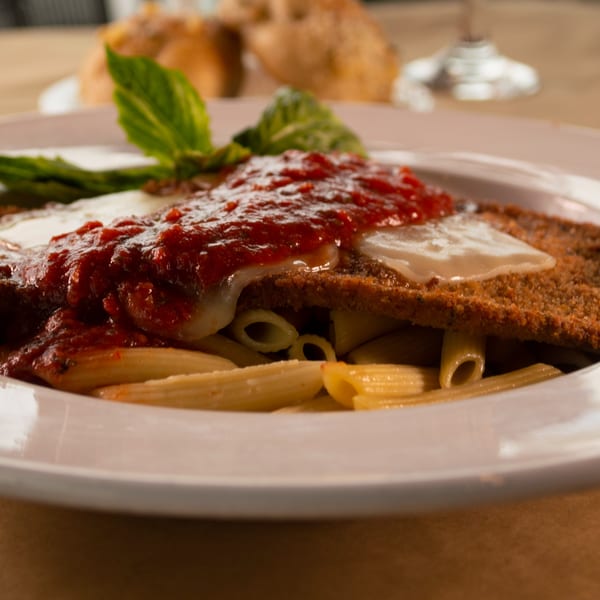 Close-up of Mike's Pizza and Pub's chicken parmesan with penne pasta, marinara, and basil.