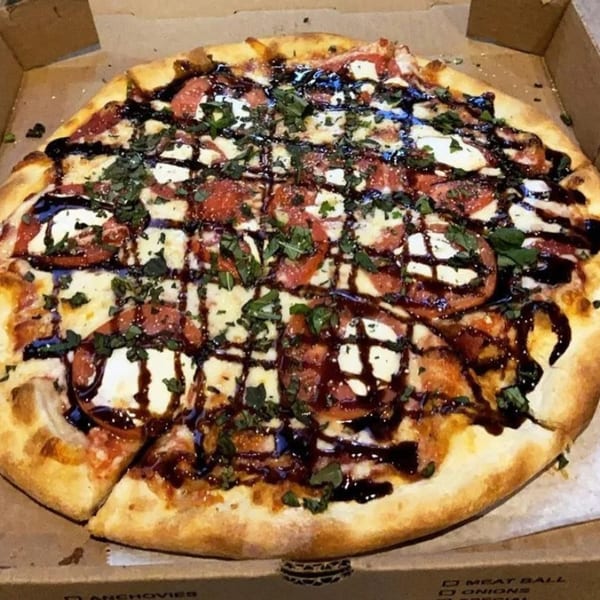 Mike's Pizza and Pub's Italian pizza with tomatoes, mozzarella, basil, and balsamic glaze in a box.