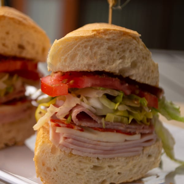 Close-up of a Mike's Pizza and Pub Italian sub sandwich with meats, cheese, lettuce, and tomatoes.